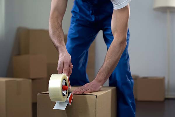 mover packing a box with tape for secure moving services in Sarasota, FL.