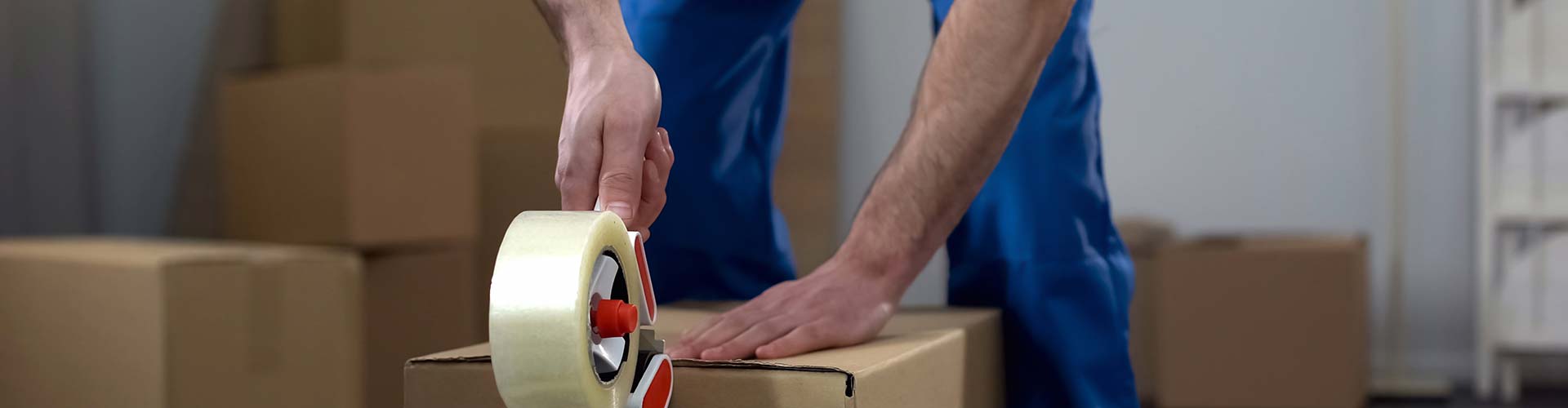  Mover sealing a box with tape as part of the packing services in Sarasota.