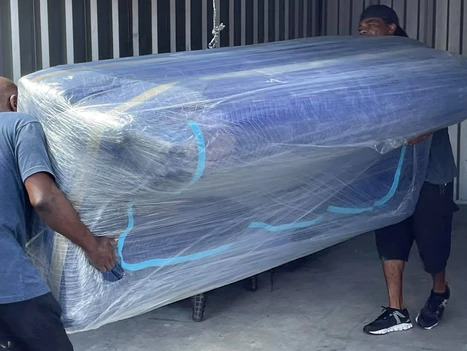 Professional movers handling a large, wrapped sofa in Sarasota.