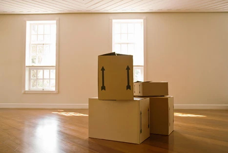 Moving boxes stacked in an empty room during a long distance move.